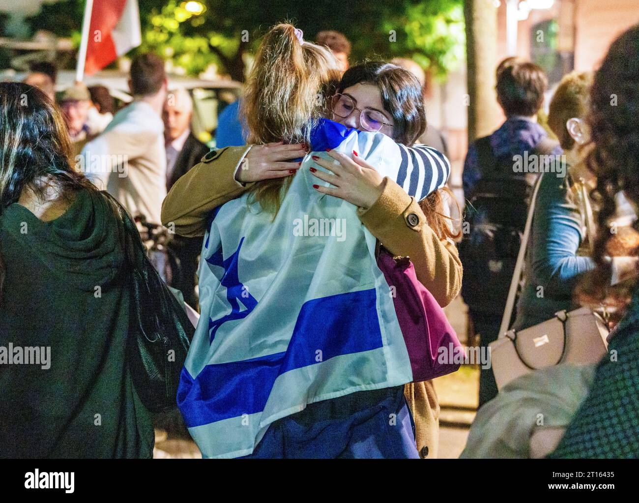 Mainz, Deutschland. Oktober 2023. Eine Frau, die in die israelische Flagge gehüllt ist, nimmt eine andere Frau in die Arme. Die Jüdische Religionsgemeinschaft Mainz-Rheinhessen und die Deutsch-israelische Gesellschaft Mainz haben unter dem Motto "Nein zum Terror, ja zu Israel" zu einer Solidaritätskundgebung aufgerufen. Darlegung: Andreas Arnold/dpa/Alamy Live News Stockfoto