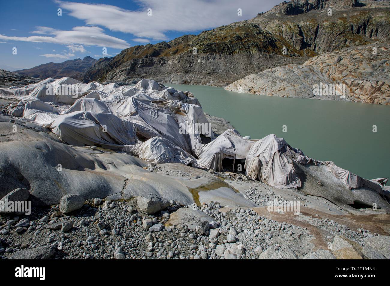 Klima | Albedo | Rhone: Riesige Vliesdecken decken decken Teile des Rhone-Gletschers in der Schweiz ab, um das unvermeidliche Schmelzen von Schnee und Eis zu verhindern. 2018 schmolz der Rhone-Gletscher (im Bild) mehr als 70 Zentimeter dick. Laut einem aktuellen Bericht der Schweizerischen Akademie der Wissenschaften verlor derselbe Gletscher in den beiden Jahren 2022/2023 über 2 Meter an Dicke. Während Schnee ein brillanter Reflektor der Sonnenenergie ist, absorbiert das dunklere Eis die Energie stattdessen und beschleunigt das Schmelzen des Gletschers. Die Farbe und Dunkelheit des Gletschereises variiert überall Stockfoto