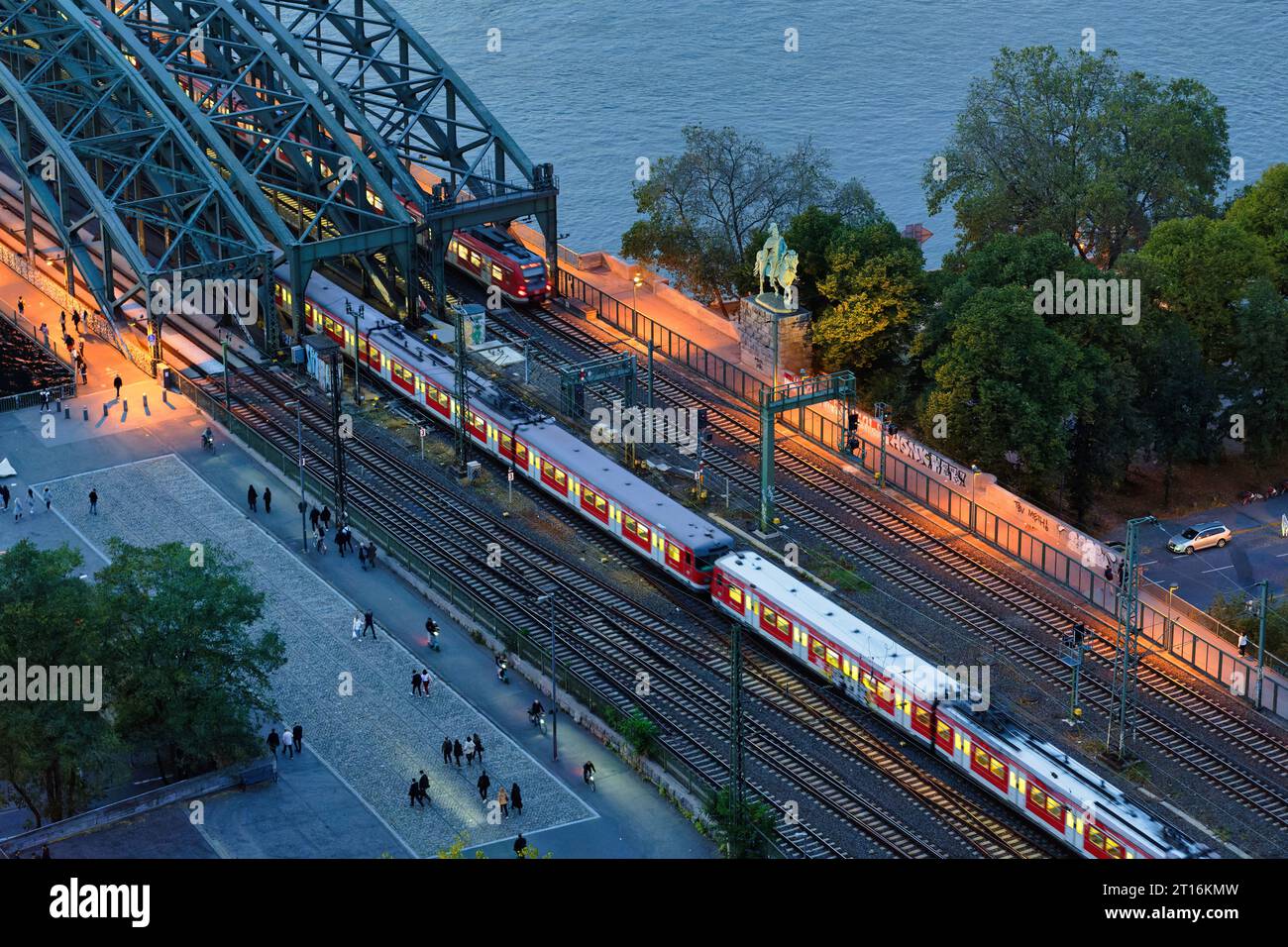 Fußgänger und Züge auf der Rampe zur hohenzollernbrücke in Richtung kölner Stadtzentrum zur blauen Stunde Stockfoto