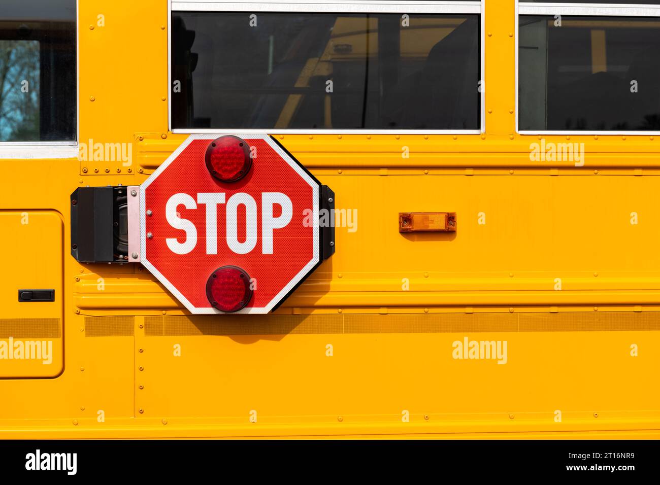 Ein großes rotes Stoppschild neben einem gelben Schulbus. Stockfoto