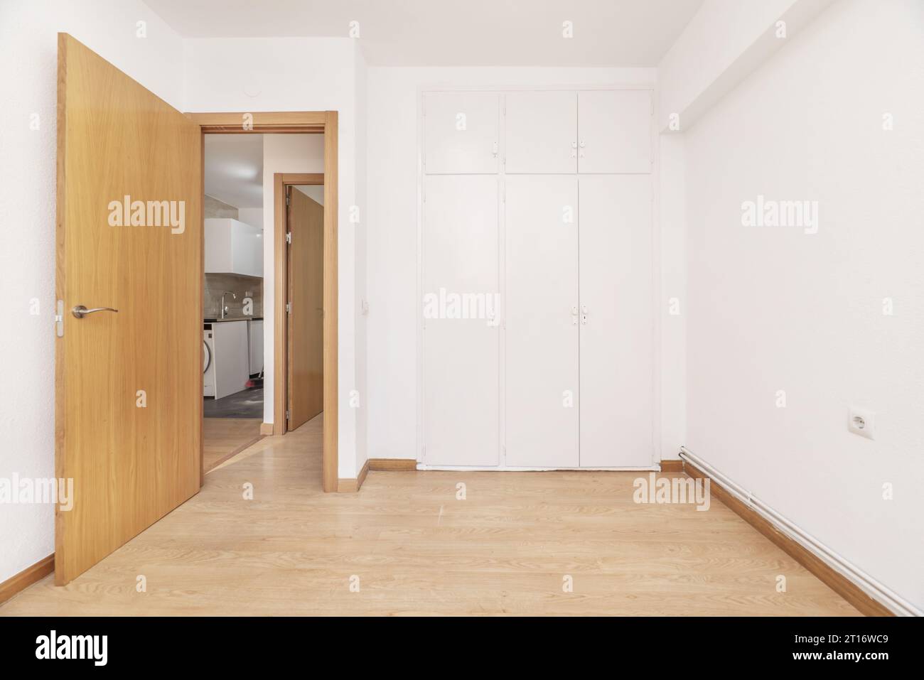 Ein leeres Zimmer mit eingebautem Kleiderschrank mit weißen Türen und frisch gestrichenen glatten Wänden Stockfoto