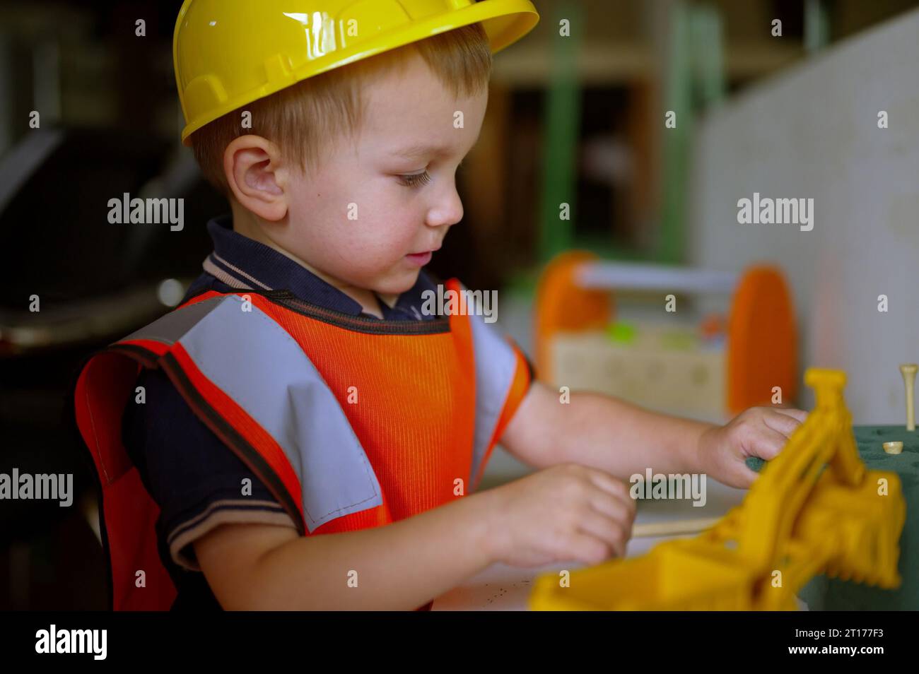 Ein kleines Kleinkind, das als Baumeister gekleidet ist und zu Hause spielt Stockfoto