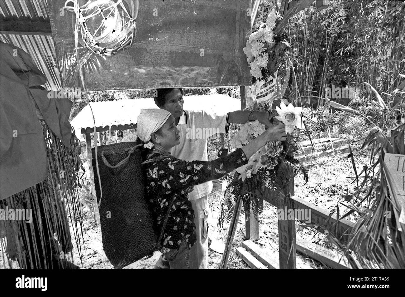 West Kalimantan, Indonesien. März 2007. Moses Salo, traditioneller Häuptling der Longhouse-Gemeinde Dayak Tamambaloh, begleitet seine Frau, während sie Blumen am Grab des ehemaligen Häuptlings, der einige Wochen zuvor verstorben ist, im Dorf Sungai Uluk Palin (Sungulo Palin), Putusibau Utara, Kapuas Hulu, West Kalimantan, Indonesien, arrangiert. Die herrschende Familie der indigenen Gemeinde, die im längsten Langhaus Kalimantans lebt, führt traditionelle Veranstaltungen zu Ehren des ehemaligen Häuptlings durch. Im September 2014 wurde ihr Langhaus durch einen Unfall niedergebrannt, ohne dass Ersatz gebaut wurde Stockfoto