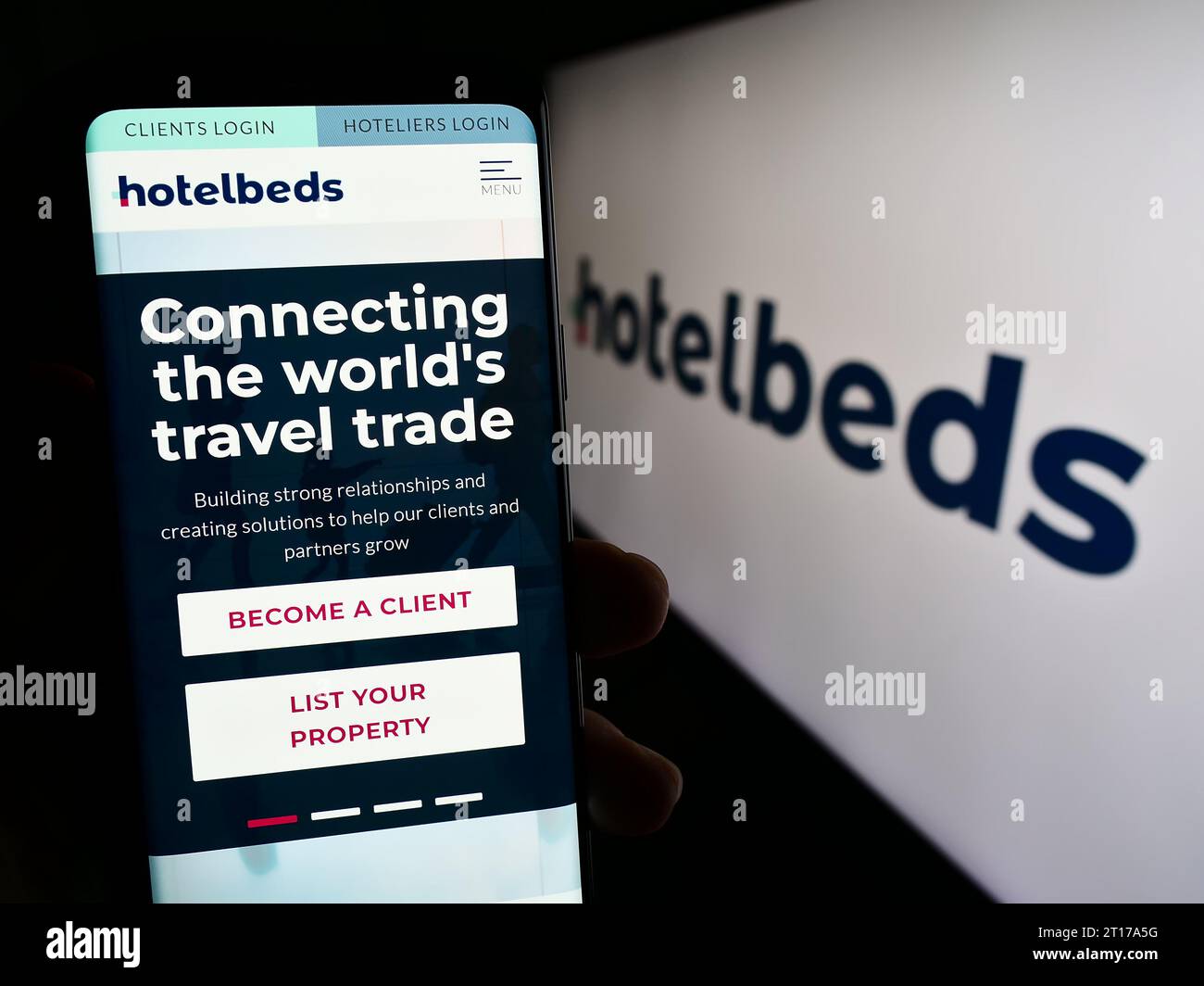 Person, die ein Mobiltelefon hält, mit Webseite des Reisetechnologieunternehmens Hotelbeds Group S.L.U. vor dem Logo. Konzentrieren Sie sich auf die Mitte des Telefondisplays. Stockfoto
