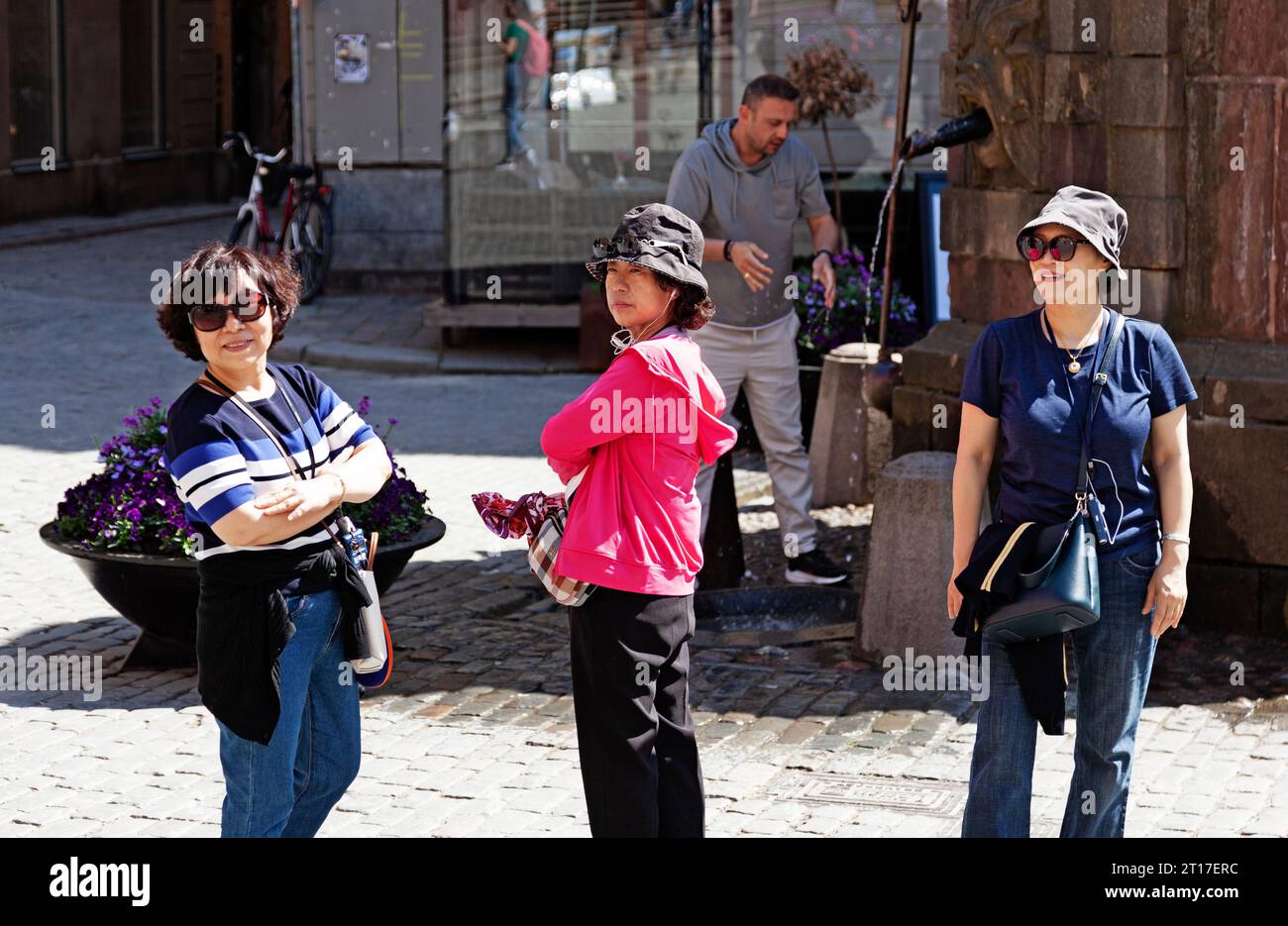 Stockholm, Schweden - 24. Mai 2023: Drei Japaner posieren am Brunnen in der Altstadt Stockfoto