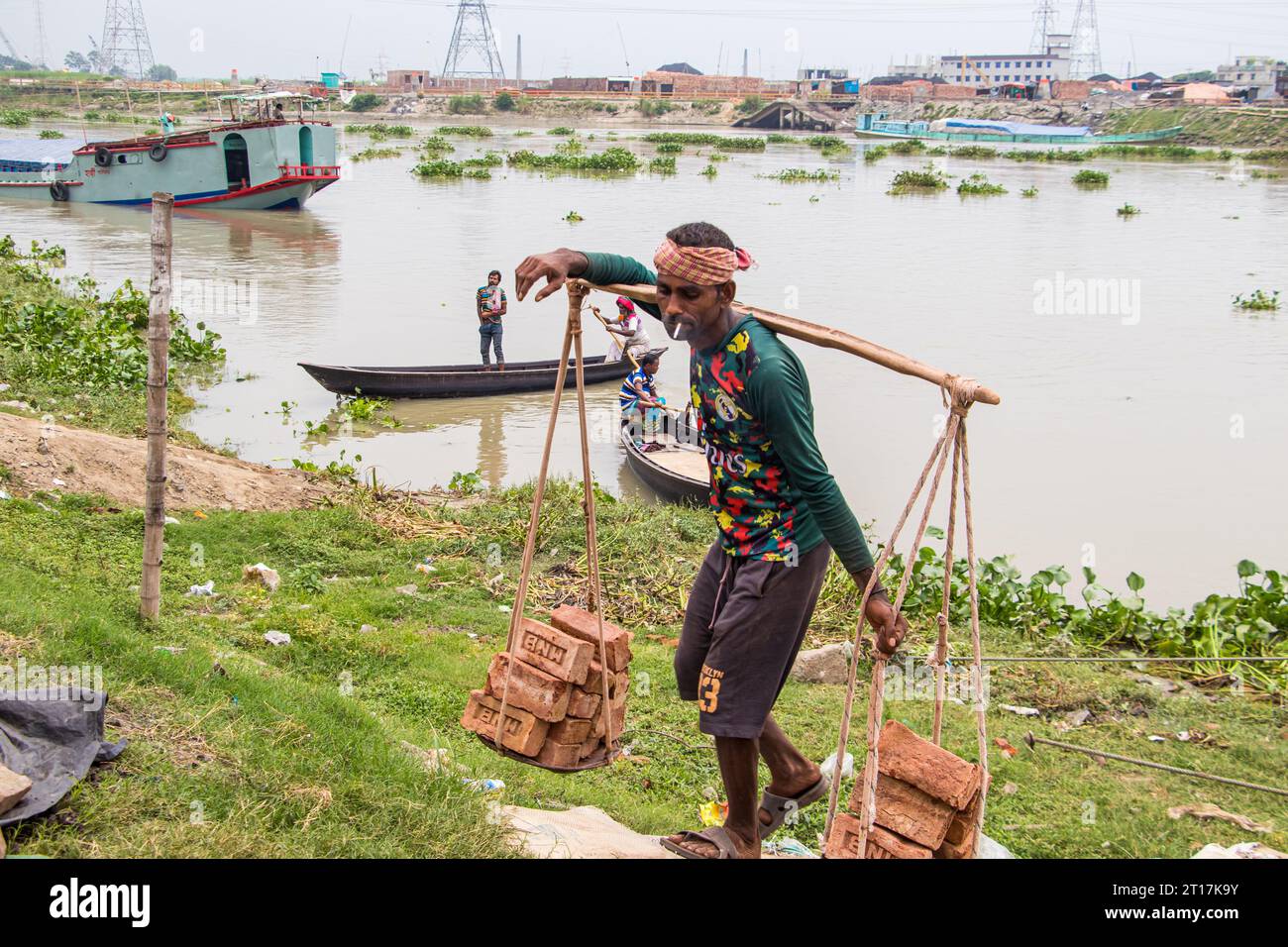 Menschen, die Ziegelsteine vom Boot abladen, das Bild, das am 29. Mai 2022 aufgenommen wurde, aus Amen Bazar, Bangladesch, wo Arbeiter schwere Ziegelsteine abladen Stockfoto