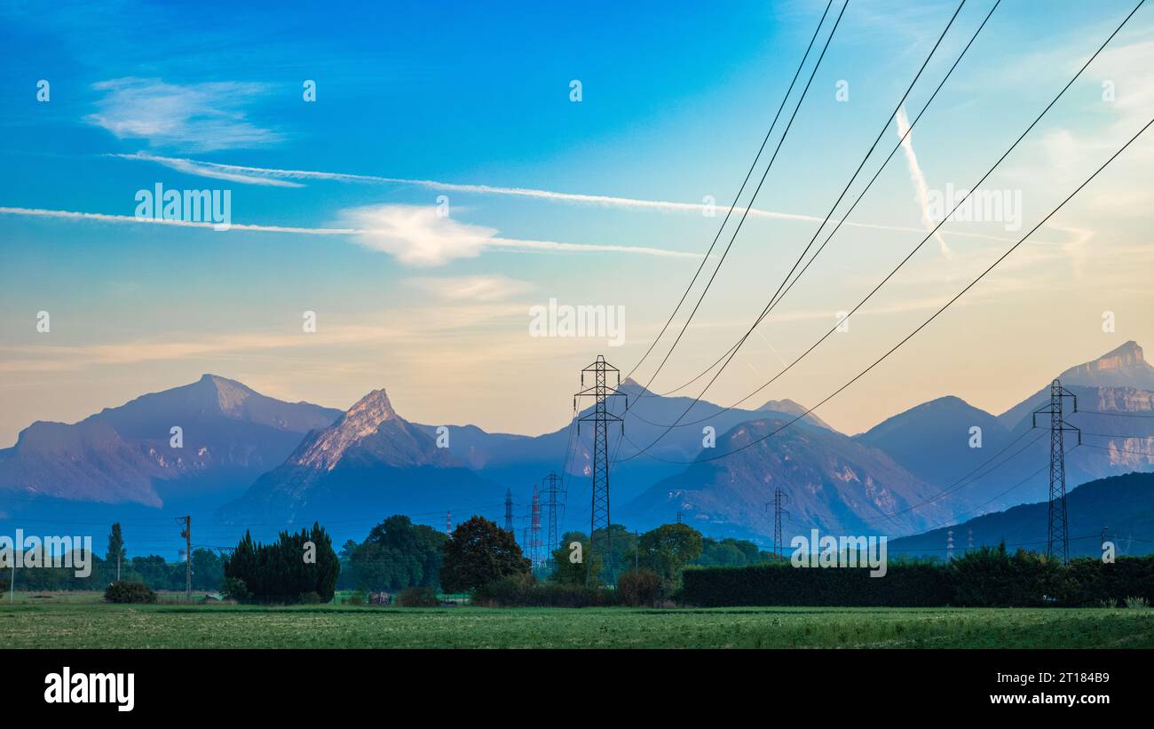 Hochspannungsleitungen und Pylonen bei Sonnenaufgang erstrecken sich über die Landschaft bis zu den Ausläufern der französischen Alpen in Varces, Franc Stockfoto