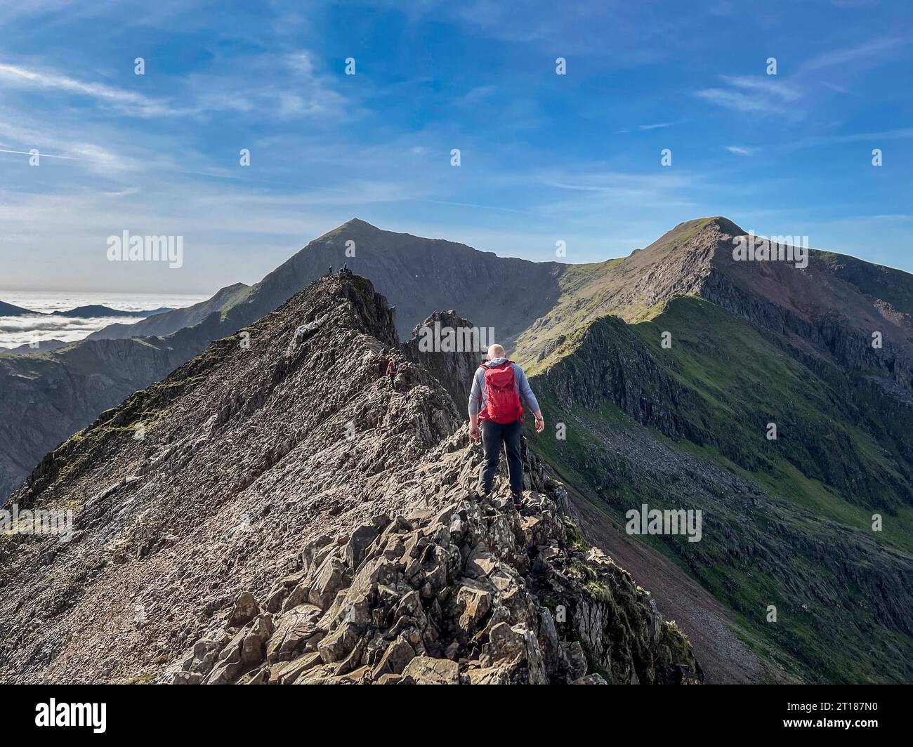 Rückansicht eines Kletterers auf Crib Goch mit CRI-y-ddysgl und Snowdon in der Ferne, an einem warmen HerbsttagWales UK Stockfoto