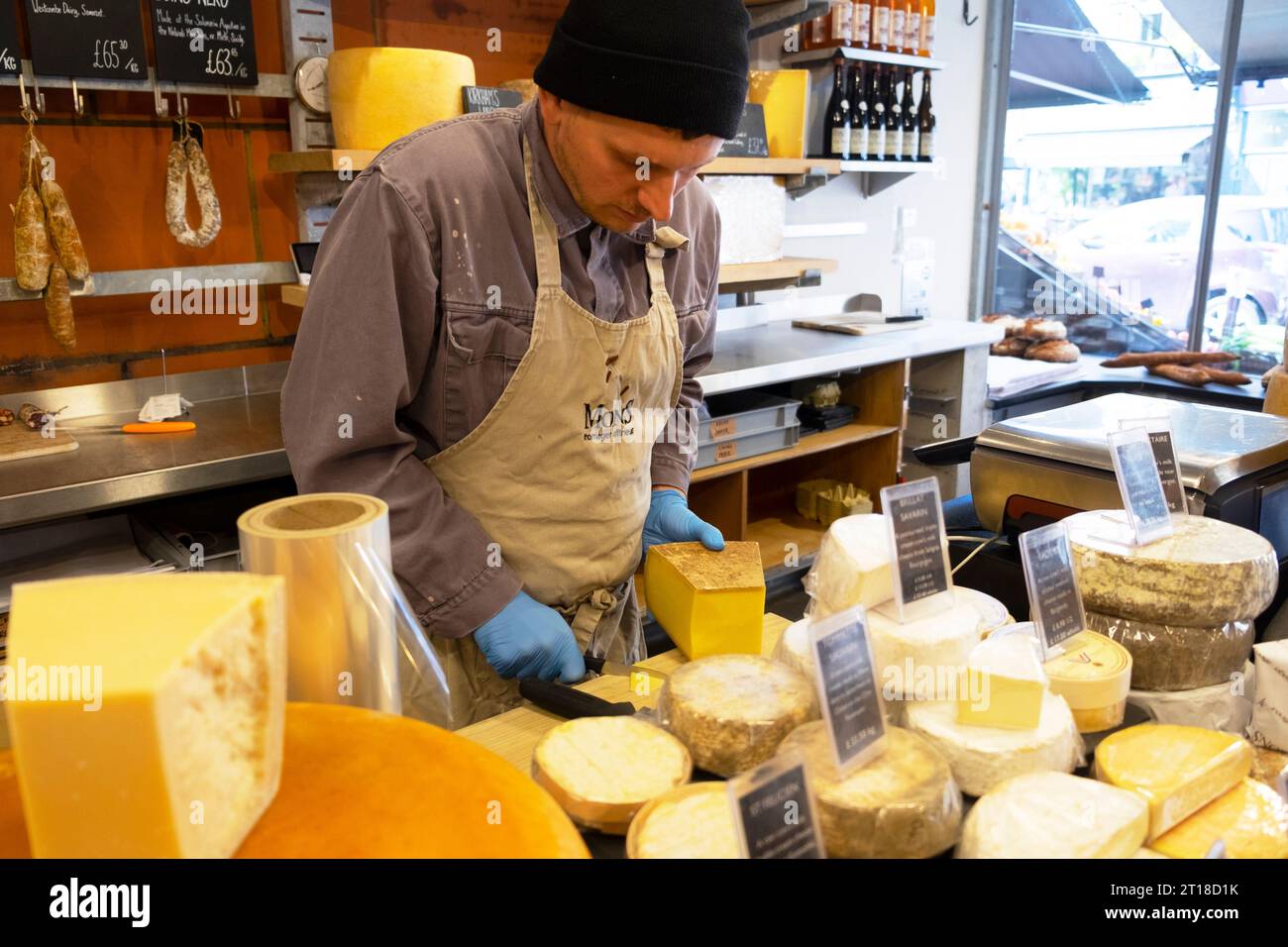Innenansicht eines Mannes, der an der Käsetheke in Mons Cheesemongers in der Lordship Lane in East Dulwich South London arbeitet SE22 England Großbritannien KATHY DEWITT Stockfoto