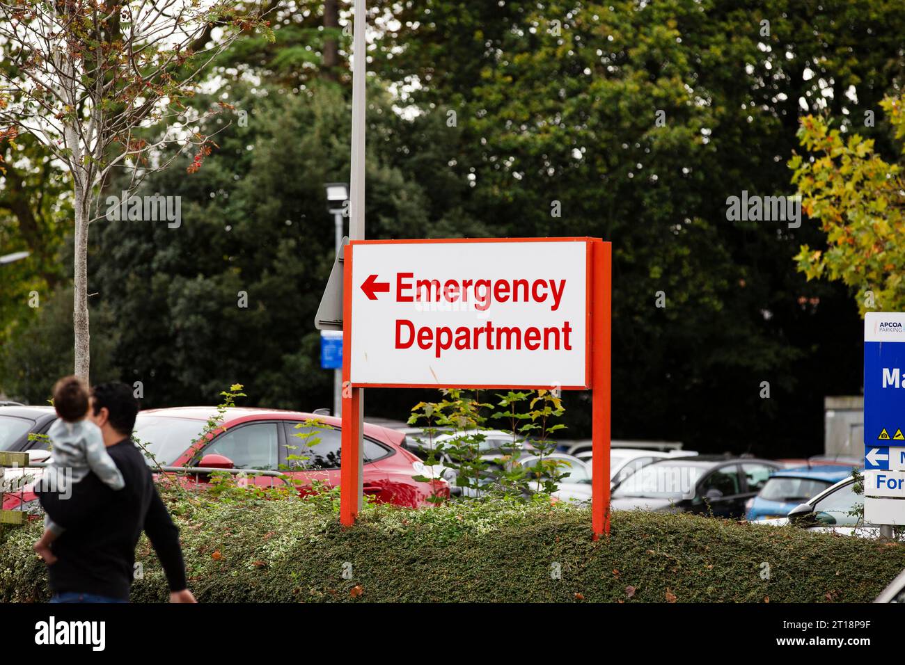 Verschwommener Mann und Kind gingen in Richtung Notaufnahme vorbei an dem Schild der roten Notaufnahme am Royal Devon & Exeter Hospital Stockfoto