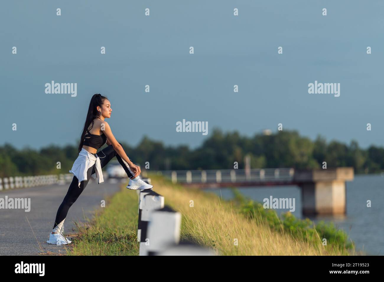 Joggerin, die an einem See steht und ihre Schnürsenkel bindet, Thailand Stockfoto
