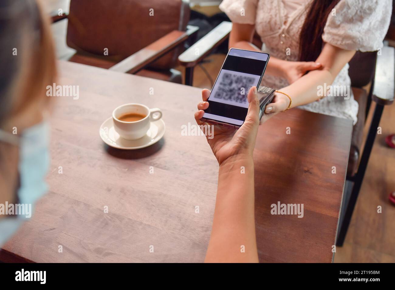 Frau scannt einen QR-Code, um eine Zahlung in einem Café zu tätigen Stockfoto