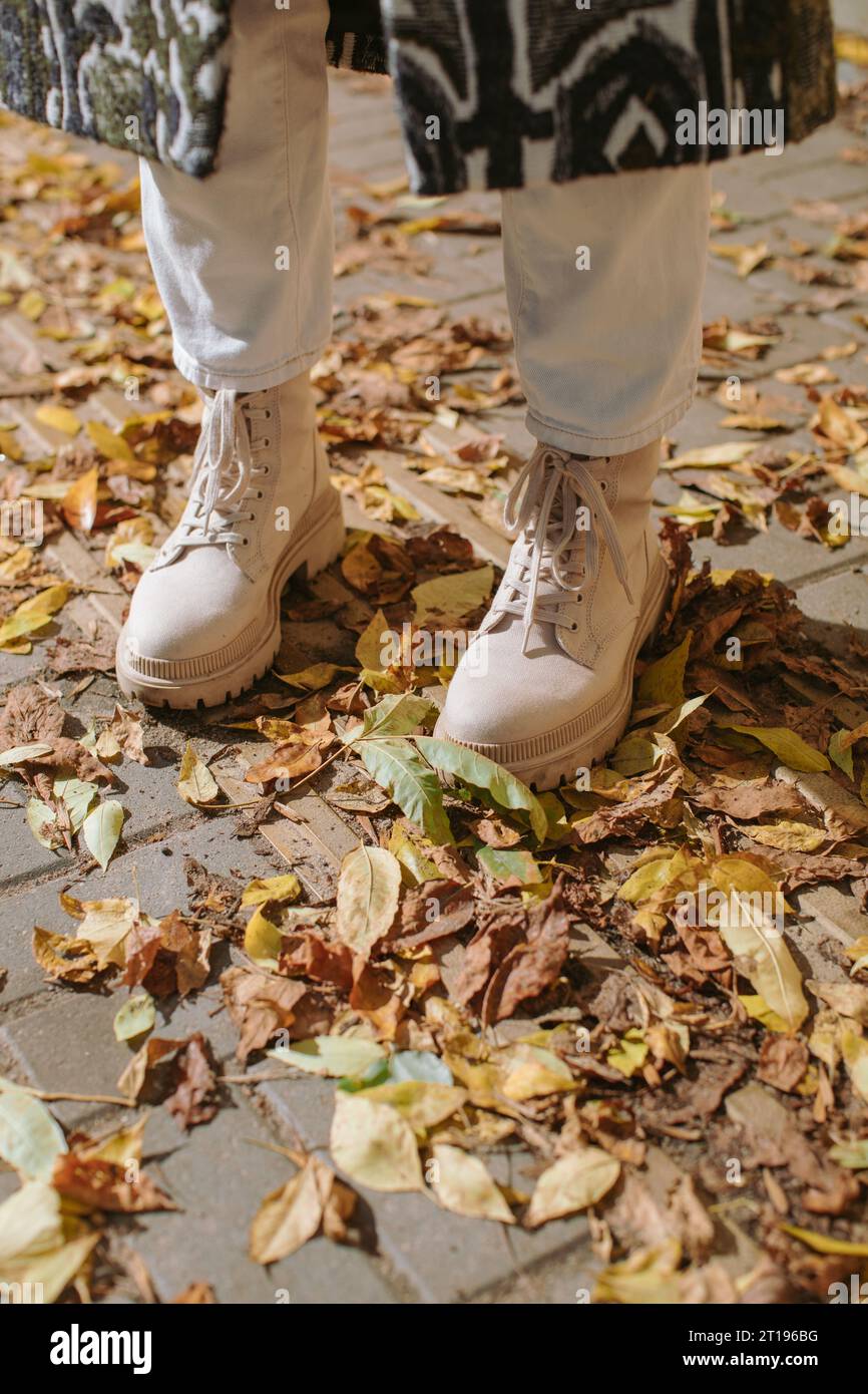 Nahaufnahme einer Frau in Stiefeln, die zwischen Herbstlaub auf der Straße steht, Weißrussland Stockfoto