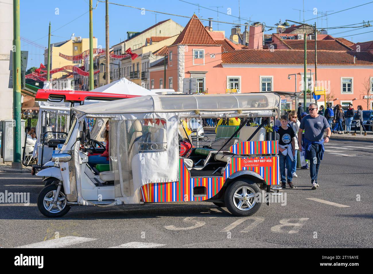 Lissabon, Portugal - 6. Januar 2023: Menschen, die auf einer Stadtstraße mit Dreiradtaxis mit städtischen Verkehrsmitteln laufen. Stockfoto