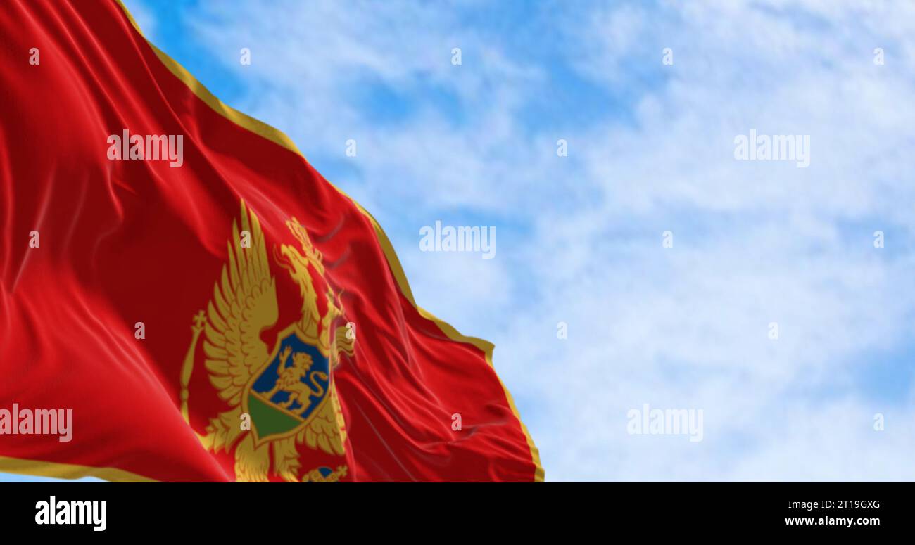 Die Nationalflagge Montenegros winkt an klaren Tagen im Wind. Rot mit goldenem Rand und in der Mitte befindet sich das Nationalwappen. 3D illus Stockfoto