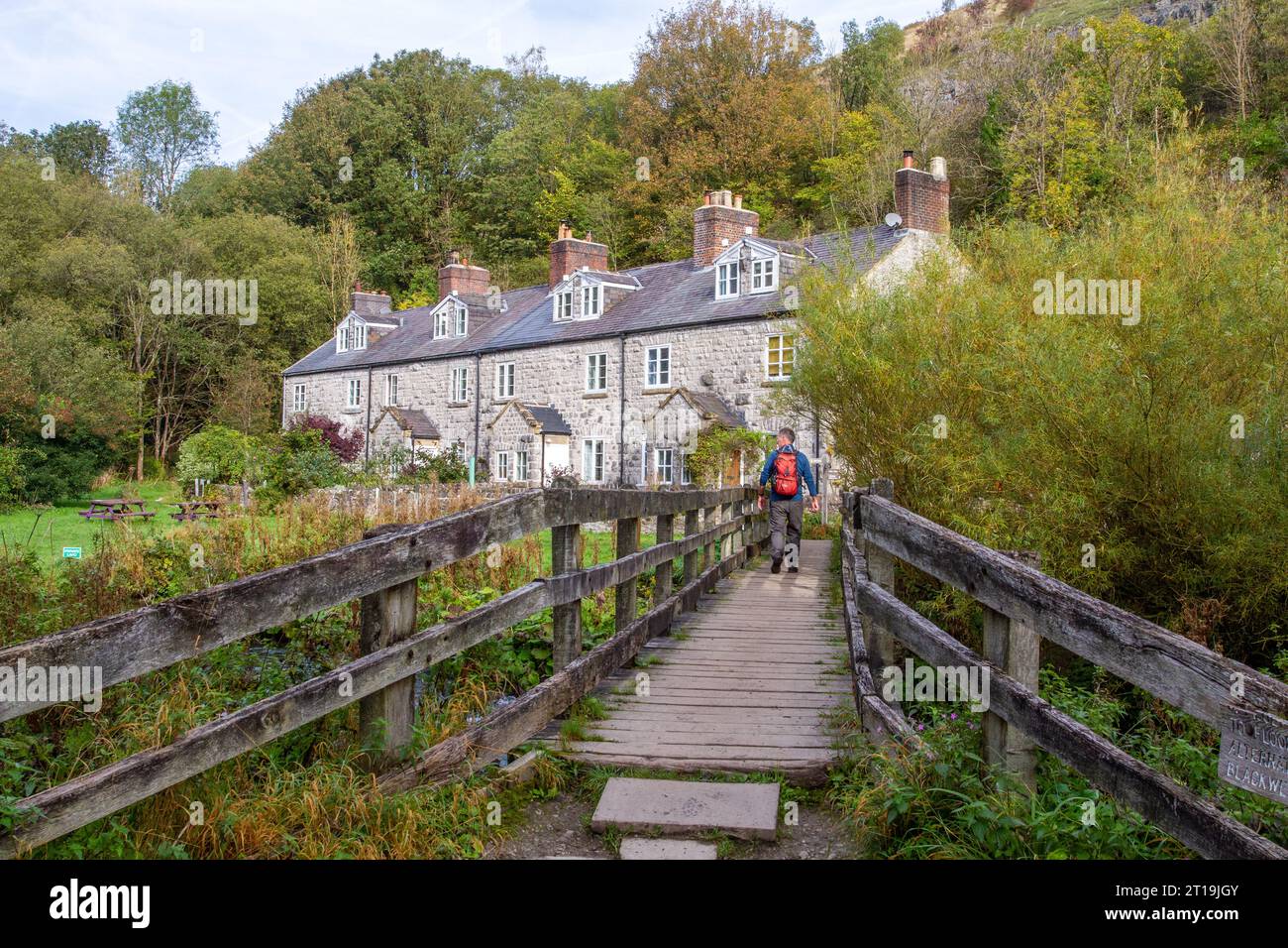 Backpacker spazieren über eine Fußgängerbrücke über den Fluss Wye bei Blackwell Mill in Monsall Dale am Anfang des Monsal Trail Derbyshire Peak District Stockfoto