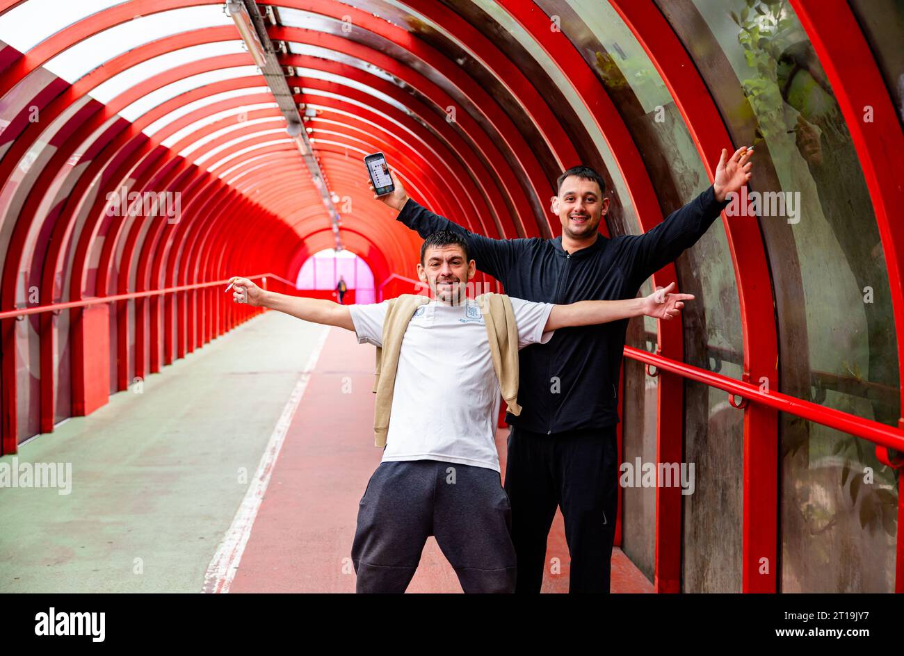 Zwei Einheimische posieren glücklich mit Handys und Zigaretten in der Hand und bestehen darauf, dass ihr Foto im SECC-Tunnel/Brücke gemacht wurde Stockfoto