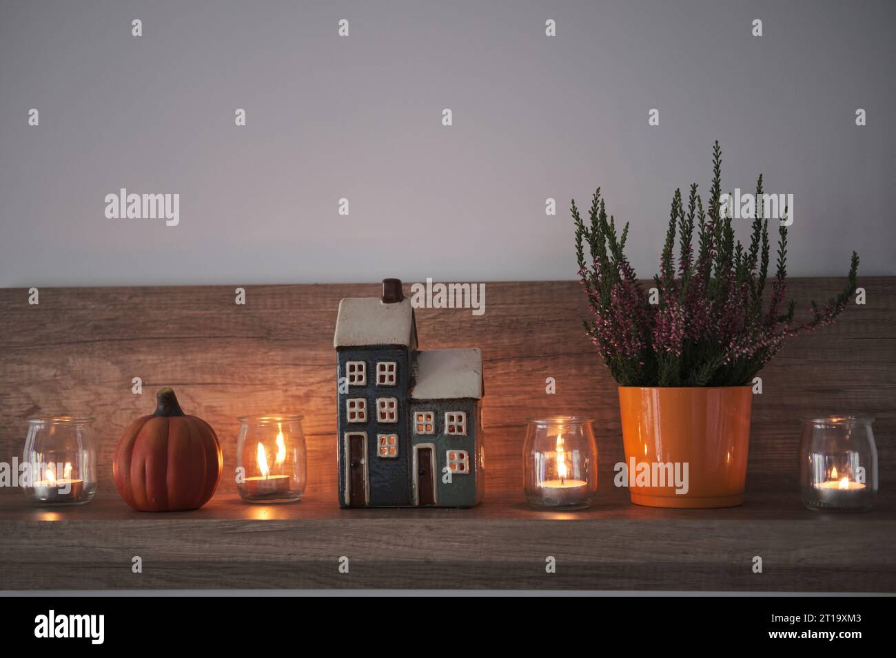 Niedliches Herbstarrangement für Hygge-Wohnkultur. Dekoratives Haus, Kerzen, Heidekraut und Kürbis. Stockfoto