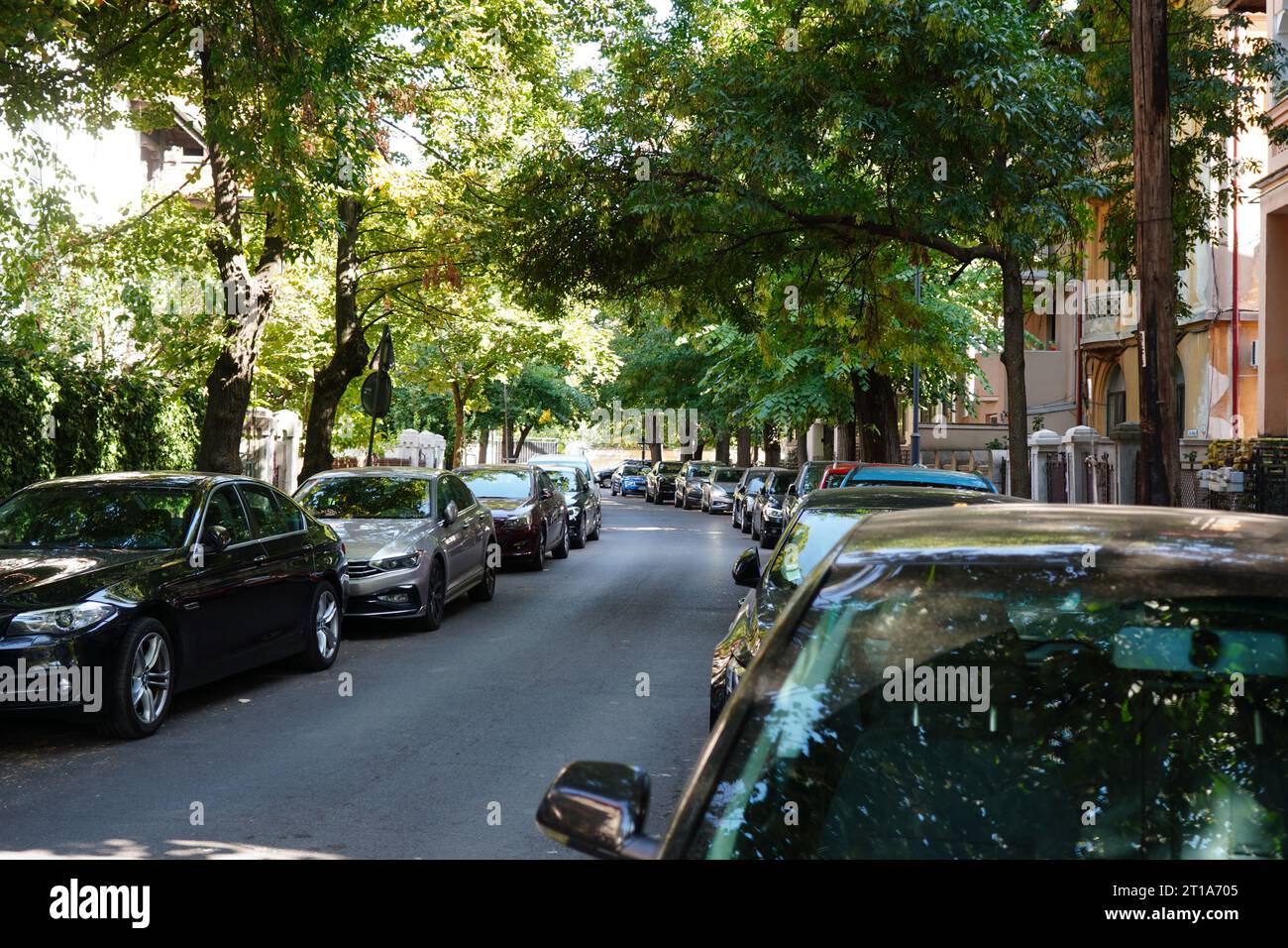 Viele Autos parkten hintereinander auf beiden Seiten einer Straße entlang von Häusern in Bukarest Stockfoto