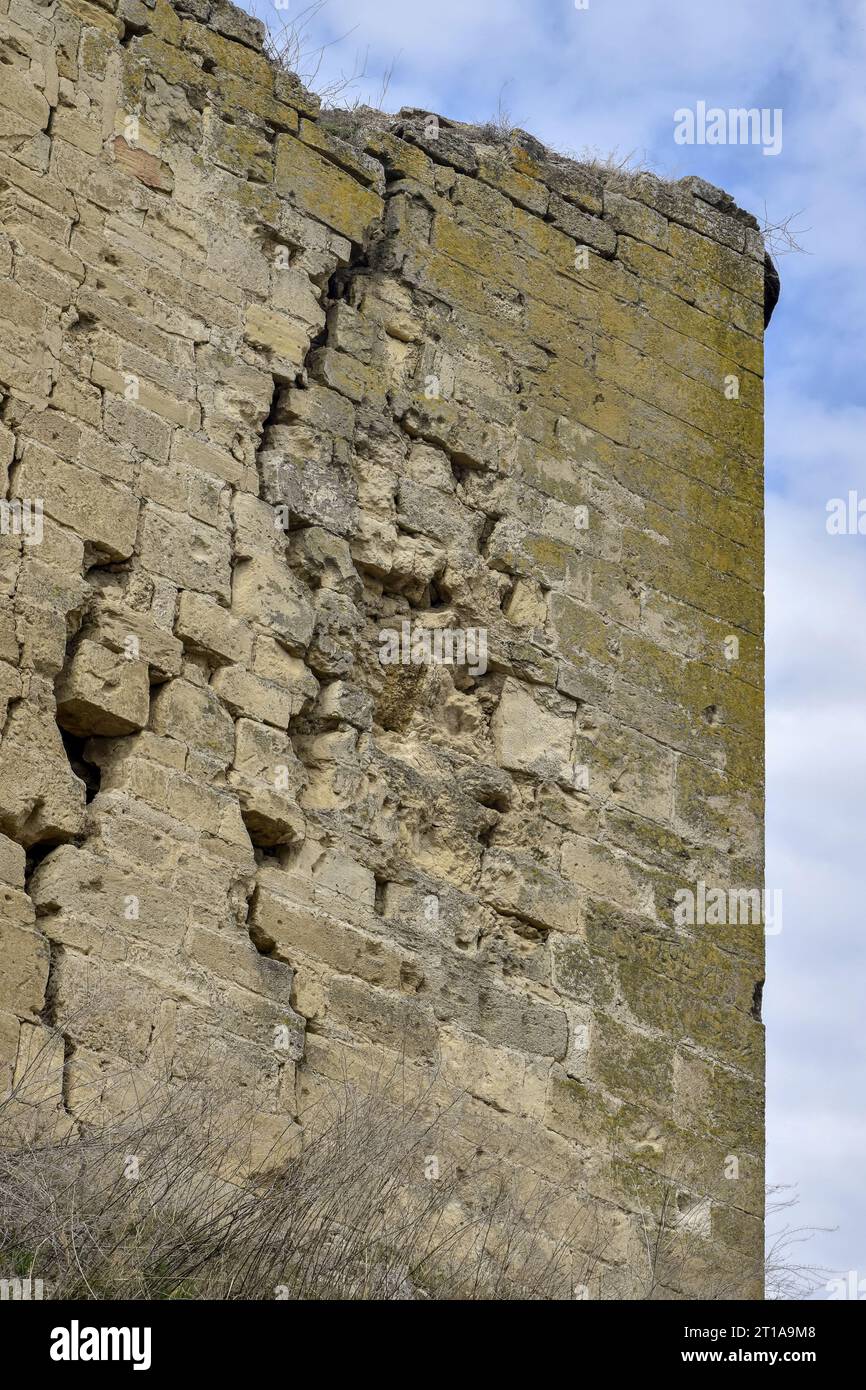 Eine alte moosbedeckte Steinmauer mit tiefen Rissen und eingestürzten Steinen auf dem Hintergrund eines bewölkten Himmels. Große diagonale Risse an der alten Wand. Spac kopieren Stockfoto Eine alte moosbedeckte Steinmauer mit tiefen Rissen und eingestürzten Steinen auf dem Hintergrund eines bewölkten Himmels. Große diagonale Risse an der alten Wand. Spac kopieren Stockfoto