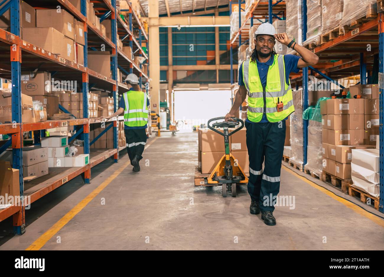 Lagermitarbeiter, die mit einem Handhubwagen oder einer Paketzustellung mit Handhubwagen vom Warenregallagerbereich aus versandt werden. Stockfoto