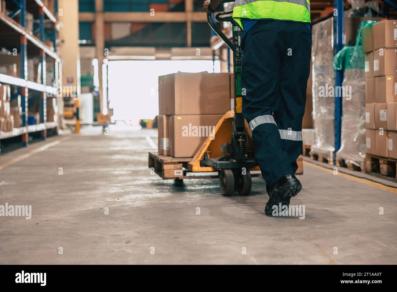 Lagerpersonal, das den Paketkasten mit einem Handhubwagen bewegt, oder manuelles Anheben von Versandgütern im Regallagerbereich. Stockfoto