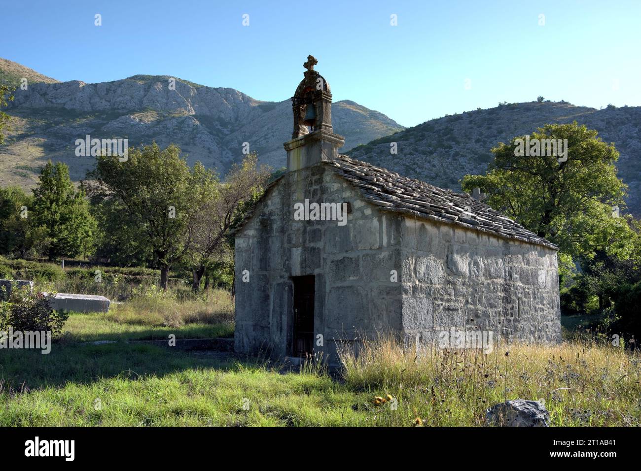 Kleine Steinkirche mit großen Grabsteinen, genannt „stecci“ in Bosnien und Herzegowina Stockfoto
