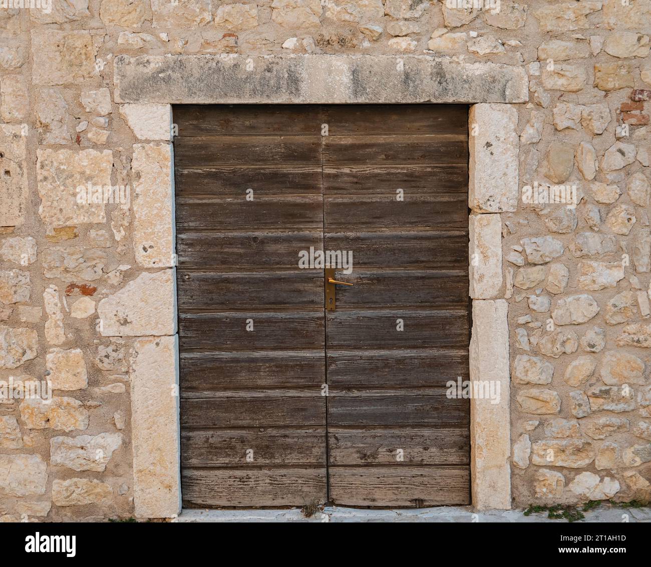 Alte Holztür in der Wand aus Kalkstein Stockfoto