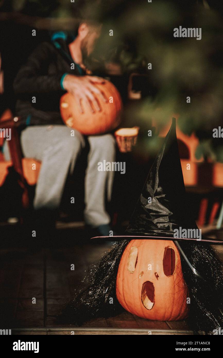 Mann schnitzt Halloween Kürbis auf der sonnigen Terrasse Stockfoto