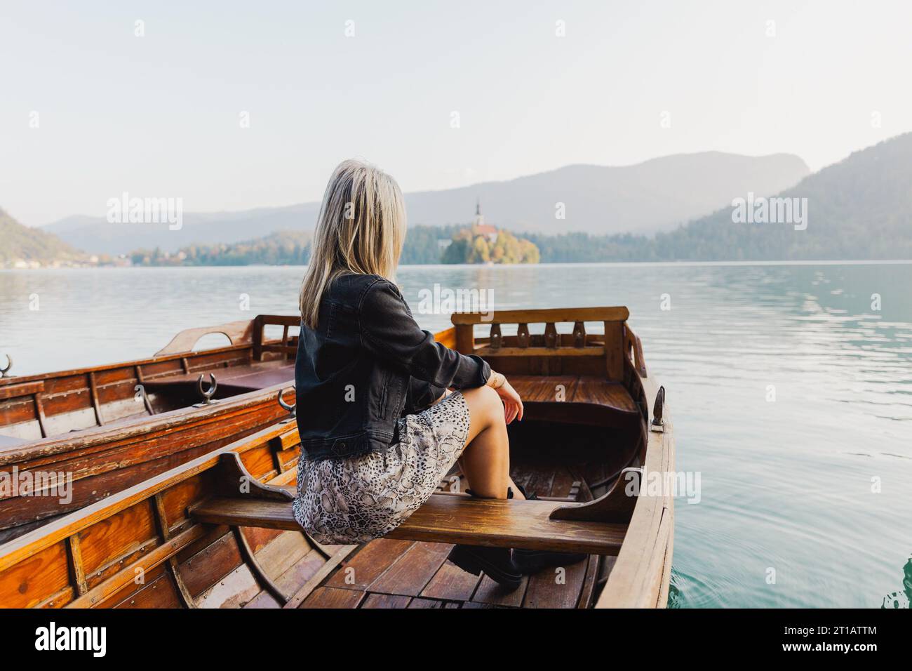Eine Frau, die auf einem Boot sitzt, beobachtet den See an einem Herbsttag, Foto von hinten Stockfoto