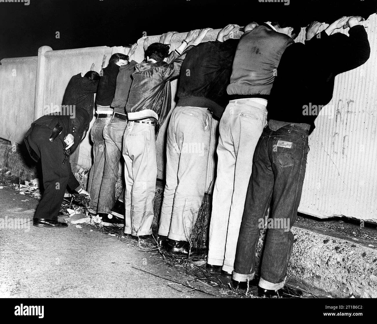 Sieben Männer stehen auf dem Zaun, als sie von einem Polizisten in der Pacific St. zwischen Carlton und Vanderbilt Avenues, Brooklyn, New York City, New York, USA, Orlando Fernandez, New York World-Telegram and the Sun Newspaper Photograph Collection, 1956 Stockfoto