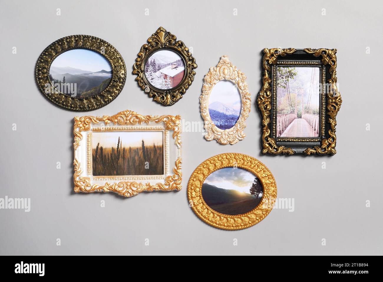 Vintage-Rahmen mit wunderschönen Fotos von Landschaften, die an einer hellgrauen Wand hängen Stockfoto