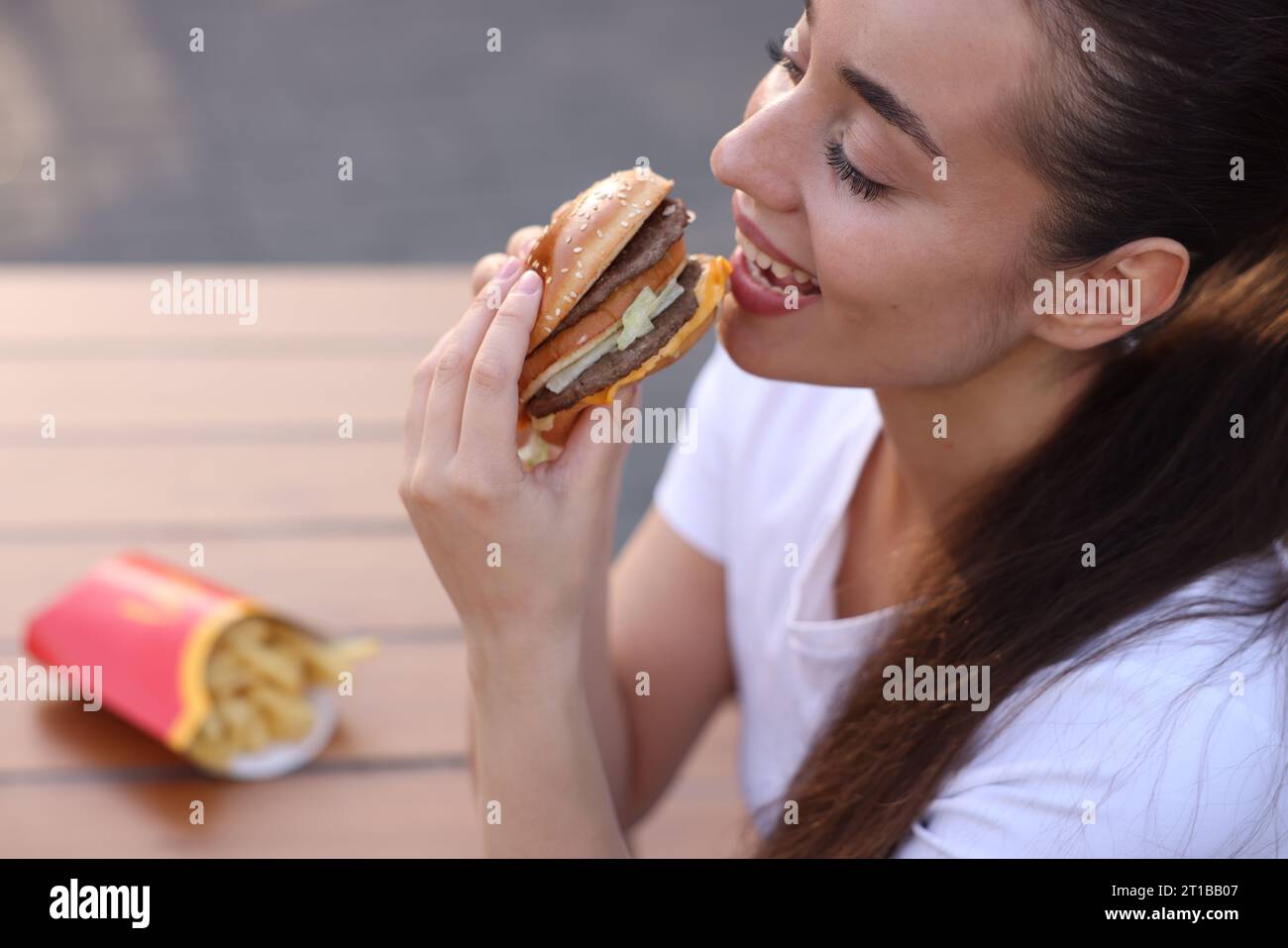 Lviv, Ukraine - 26. September 2023: Frau isst McDonald's Burger im Freien, Nahaufnahme Stockfoto