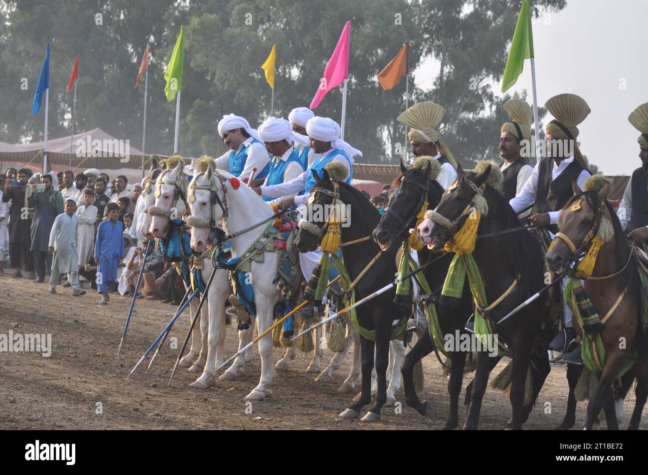 Islamabad, Pakistan. Oktober 2023. Während der jährlichen Messe (Dargah Hazrat Kulababa Sarkar Sharif Urs) im Dorf Mansar im Distrikt Attock, Provinz Punjab, fahren pakistanische Reiter auf einen Kurs, um die Stifte abzuholen. Es wurde angezeigt. Mit Girlanden und farbenfrohen Zaum geschmückt, lassen Turbanreiter ihre Speere auf kleinen Holzblöcken auf dem Pferd nieder, während sie die jahrhundertealte Tradition des Campens in Pakistan praktizieren. (Foto: Raja Imran Bahadar/Pacific Press) Credit: Pacific Press Media Production Corp./Alamy Live News Stockfoto