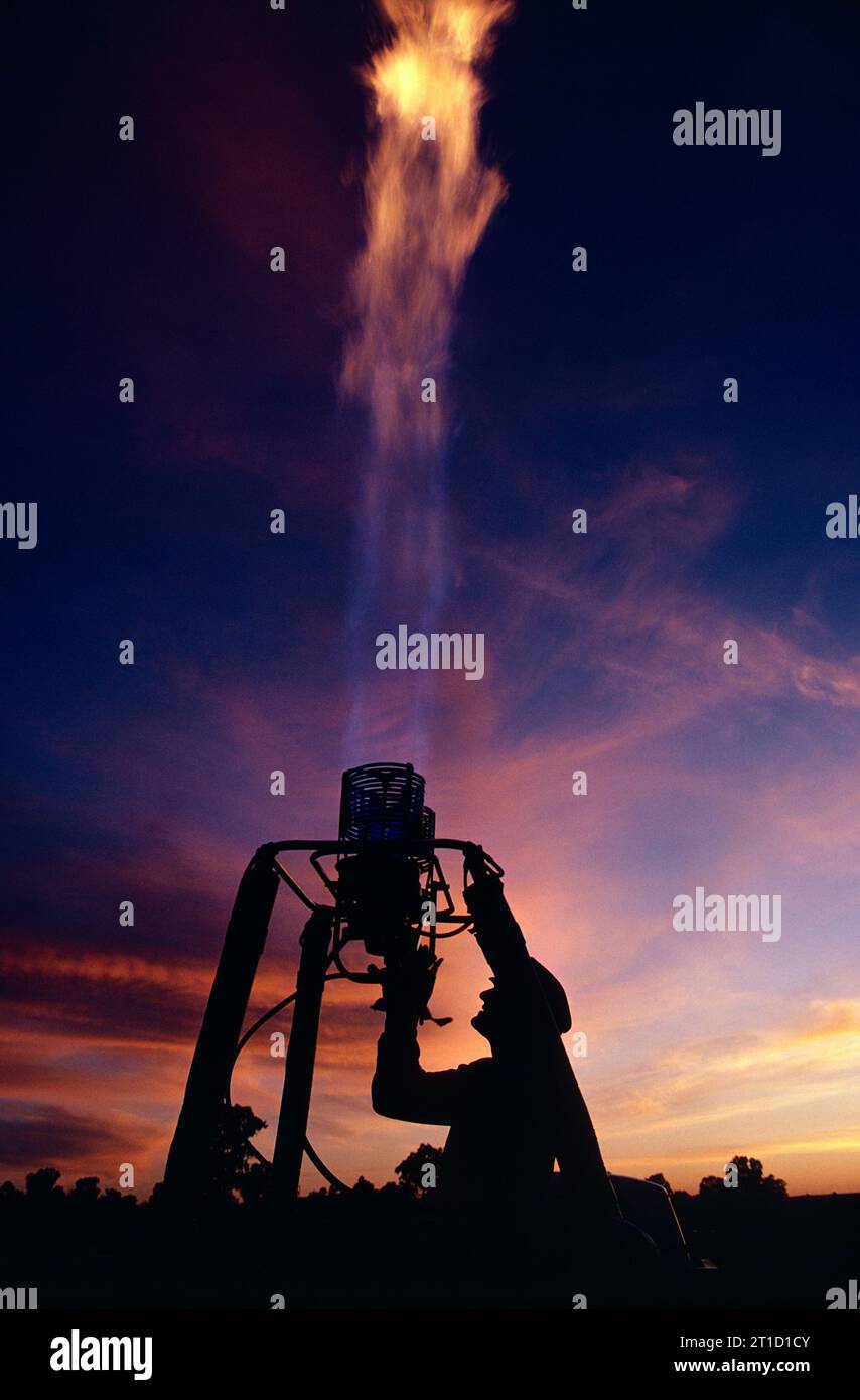 Heißluftballonfahrten. Nahaufnahme der Silhouette eines Mannes in der Nacht mit einem Brenner, der einen Ballon aufbläst. Stockfoto