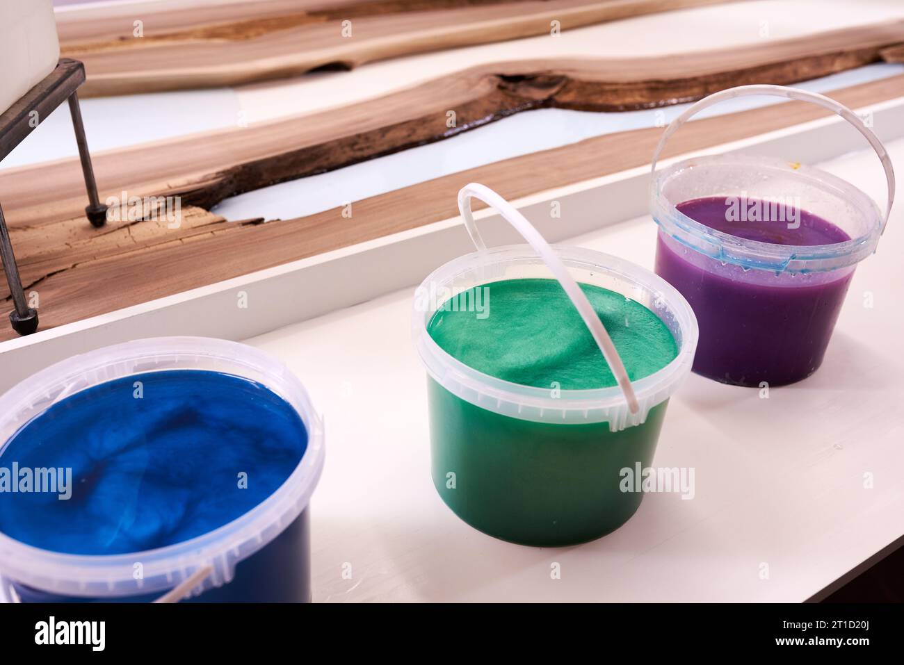 Prozessfertigung eines Kunstharz- und Holztisches. Flüssiges Epoxid wird in eine Form mit Holzrohlingen gegossen. Nahaufnahme Stockfoto