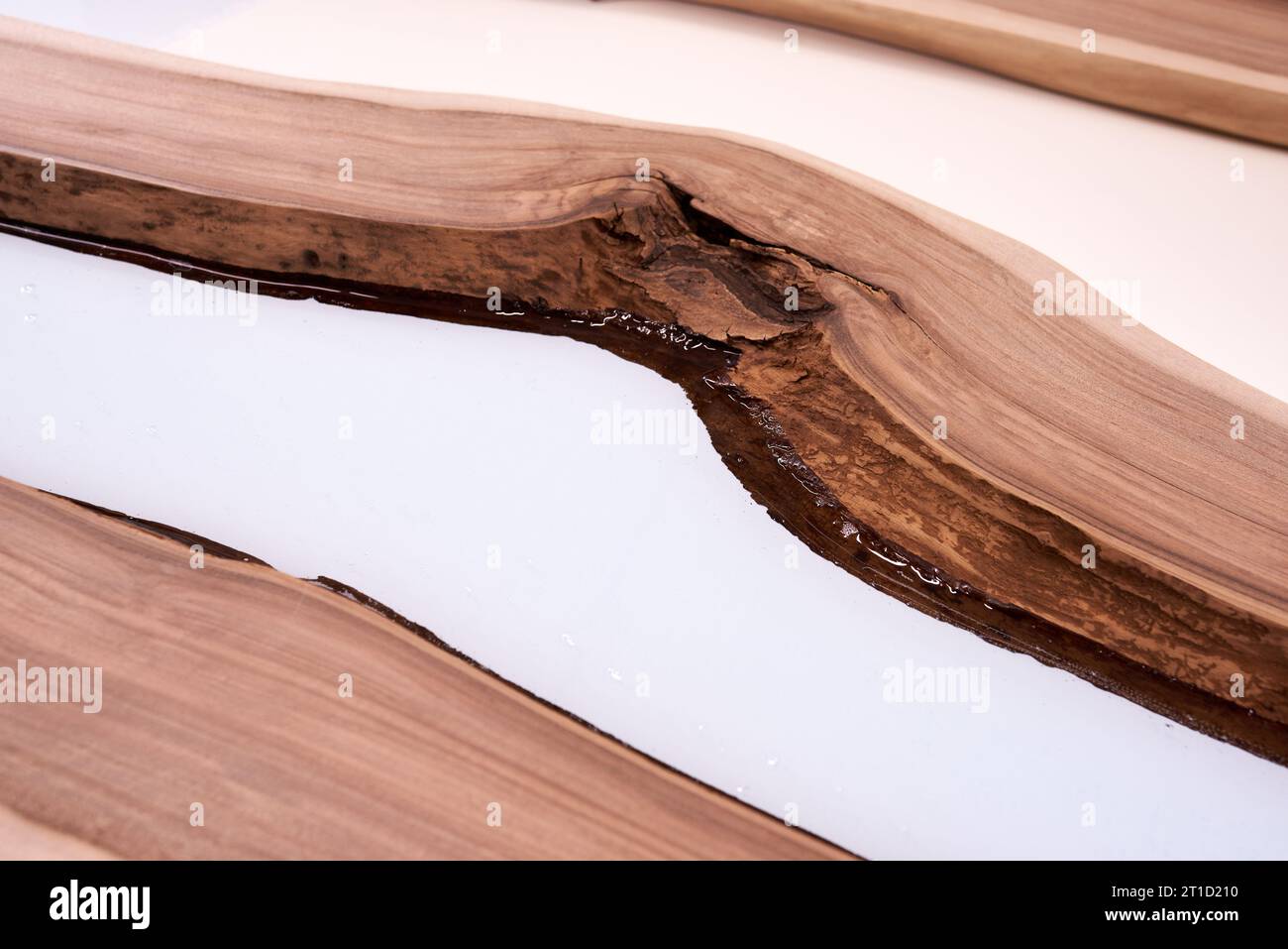 Prozessfertigung eines Kunstharz- und Holztisches. Flüssiges Epoxid wird in eine Form mit Holzrohlingen gegossen. Nahaufnahme Stockfoto