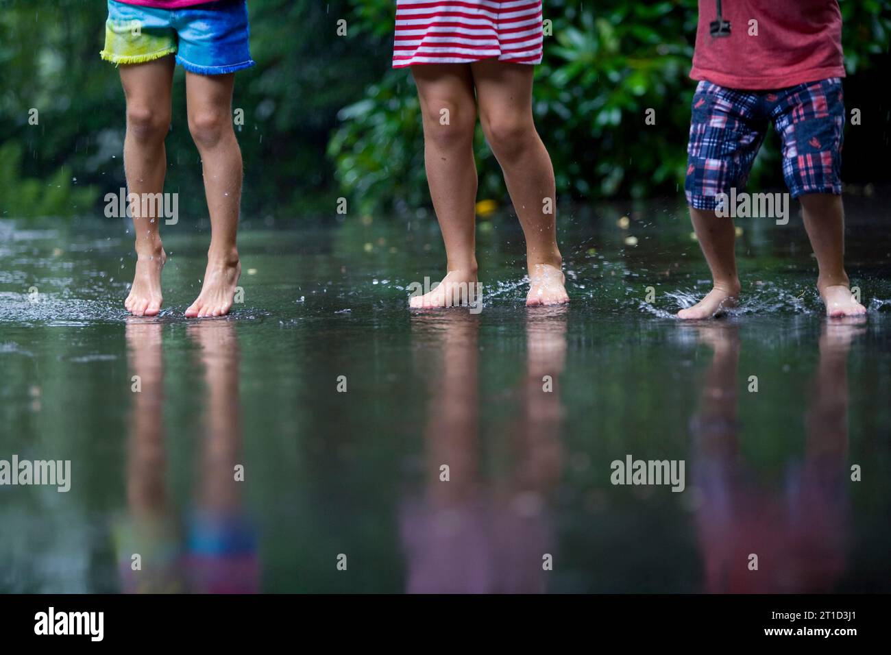 Drei kleine Kinder, die im Regen spucken Stockfoto