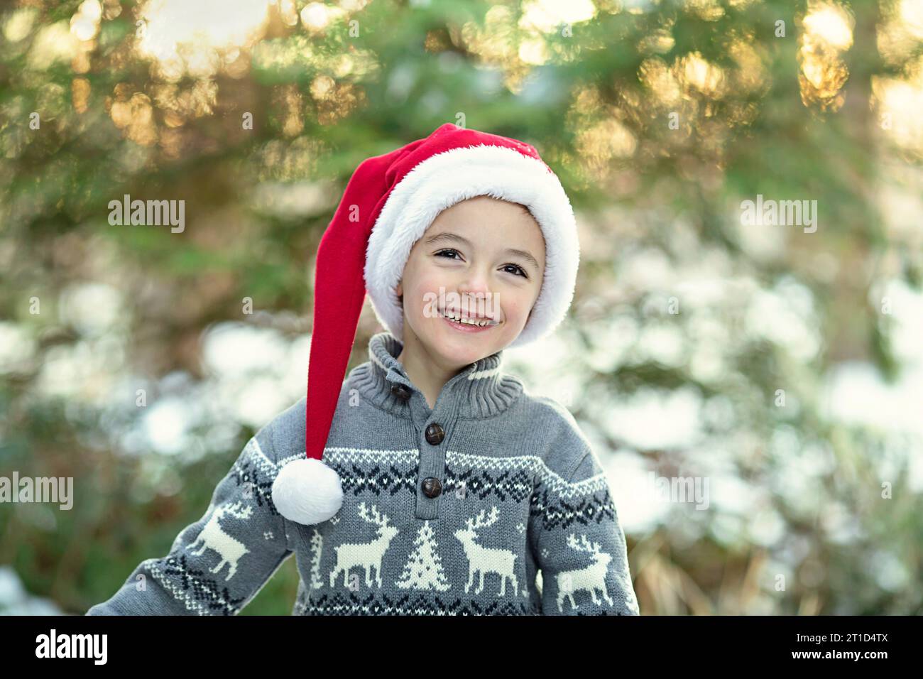 Kleiner Junge lächelnd mit weihnachtsmann-Hut und Winterpullover Stockfoto