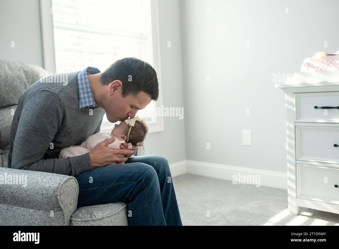 Neuer Vater küsst seine neugeborene Tochter in der Kinderkrippe Stockfoto