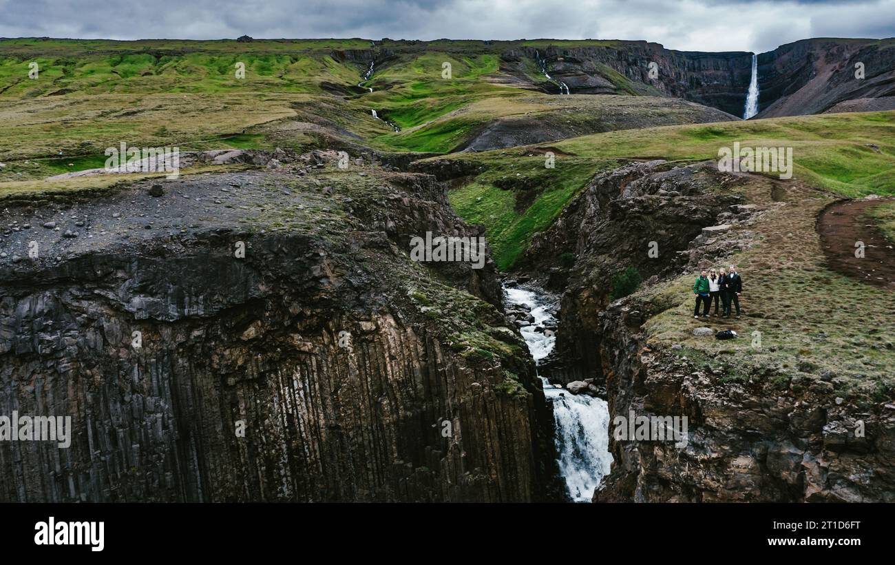 Menschen auf Abenteuertour mit Wasserfällen, die die grünen Berge hinunterragen Stockfoto
