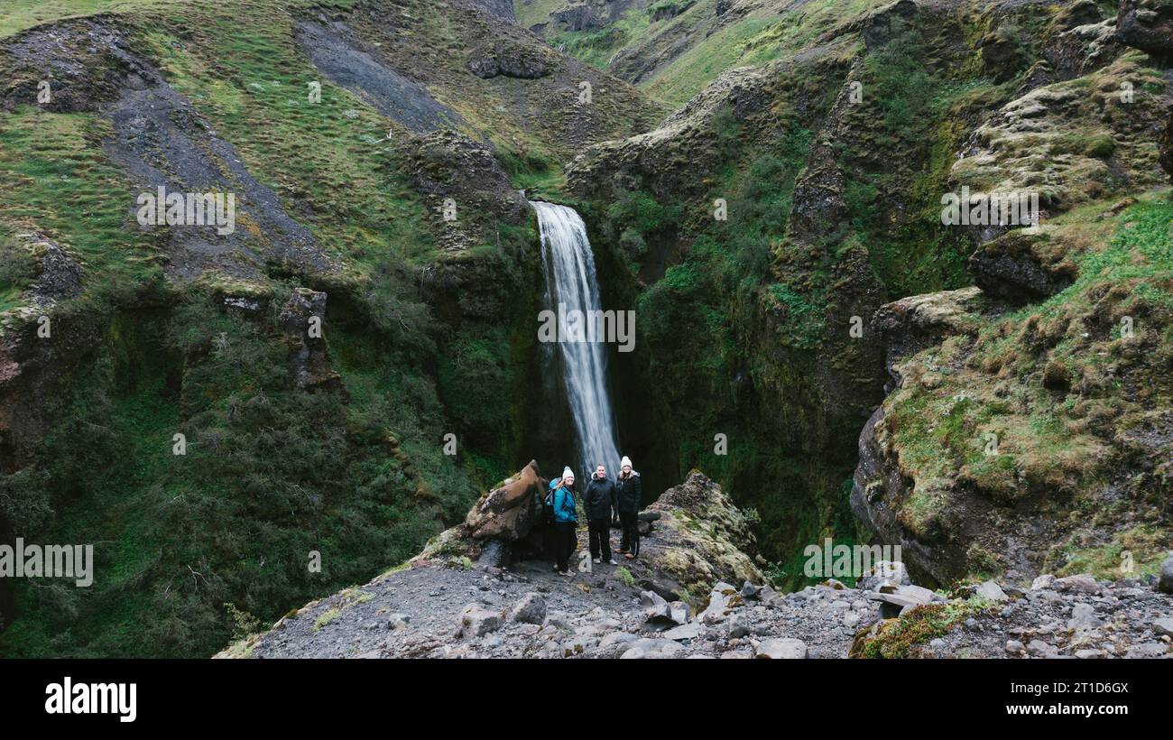 Menschen auf Wanderungen über den Wasserfall auf Klippen mit grünen Hügeln Stockfoto