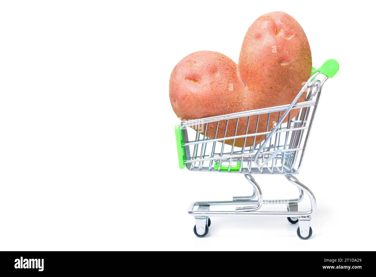 Rohe herzförmige Kartoffel in einem winzigen Einkaufswagen isoliert auf weißem Hintergrund. Konzept für Online-Lebensmittel-Marktplätze. Stockfoto