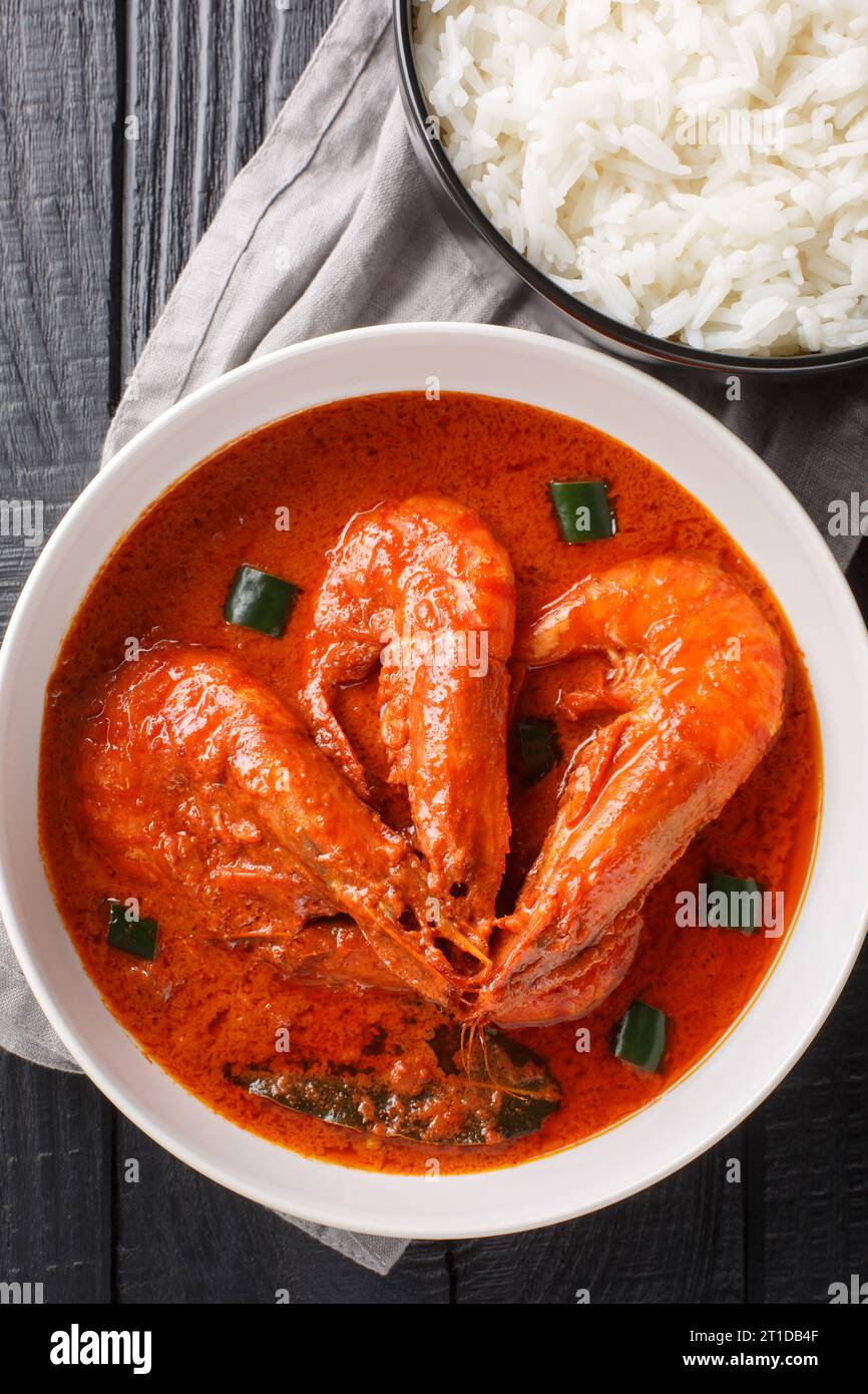 Cremiges und köstliches Garnelen-Malai-Curry mit weißem Reis auf dem Holztisch. Vertikale Draufsicht von oben Stockfoto