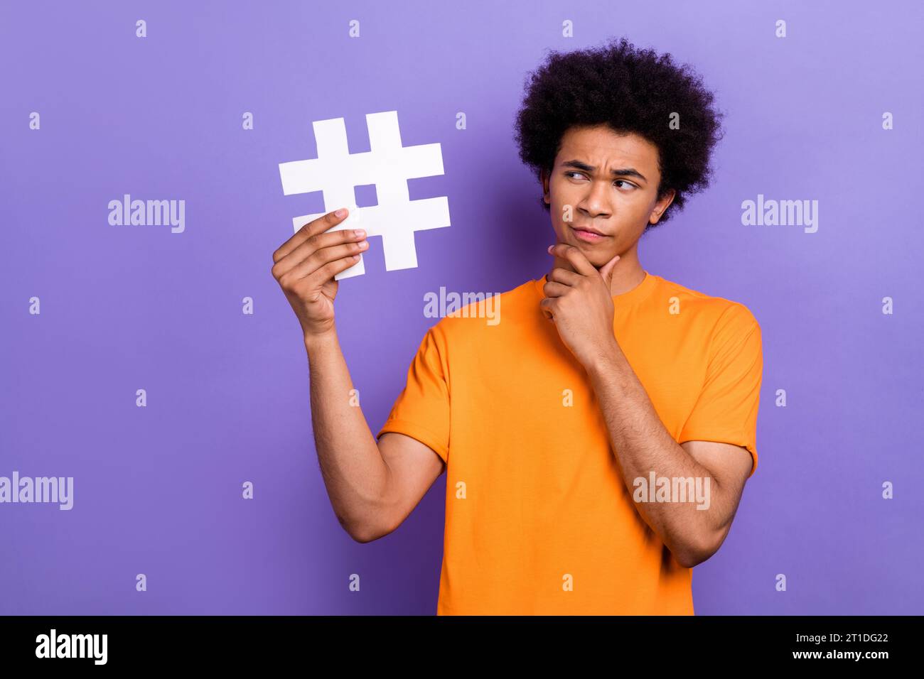 Foto von Smart Young man Touch Kinn Erraten Sie, wie Sie einen neuen tiktok Media Trend mit Hashtag-Symbol isoliert auf violettem Hintergrund erstellen Stockfoto