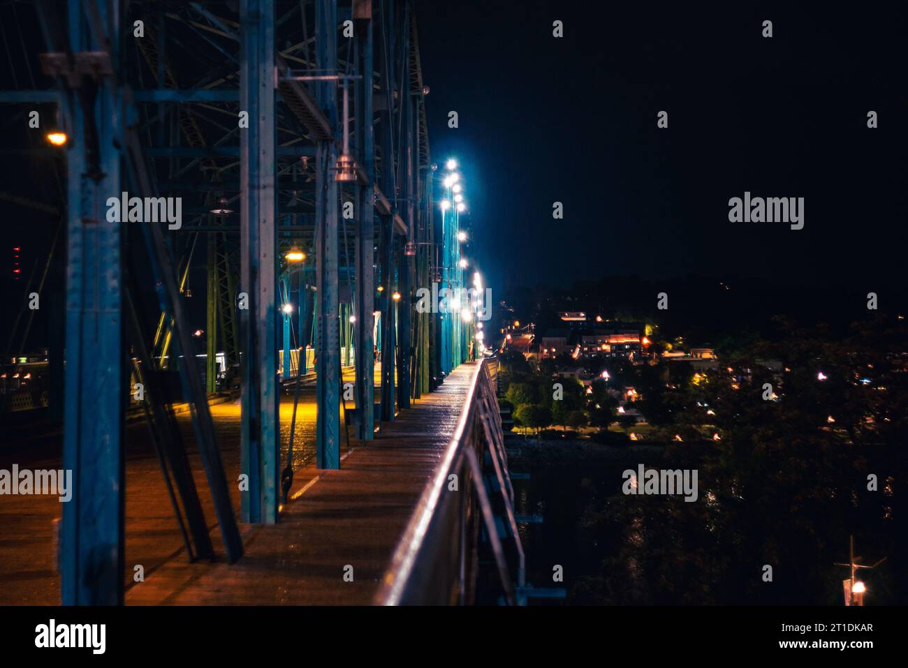 Ein beschaulicher Weg, der von smaragdfarbenen Lichtern beleuchtet wird und von hoch aufragenden Gebäuden am Abend umgeben ist Stockfoto