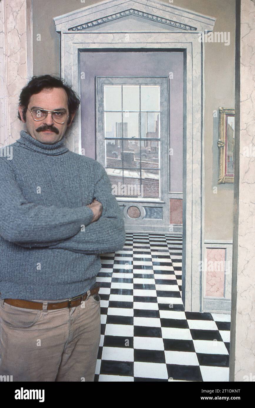 Der Trompe-L’Oiel-Künstler Richard Haas steht vor einer seiner Werke. 1977 in seinem Greenwich Village Loft in Soho, New York City. Es ist eine bemalte Lobby zu einem zusätzlichen Zimmer mit Aussicht, die man sehen würde, wenn es wirklich eine Terrasse gibt. Stockfoto