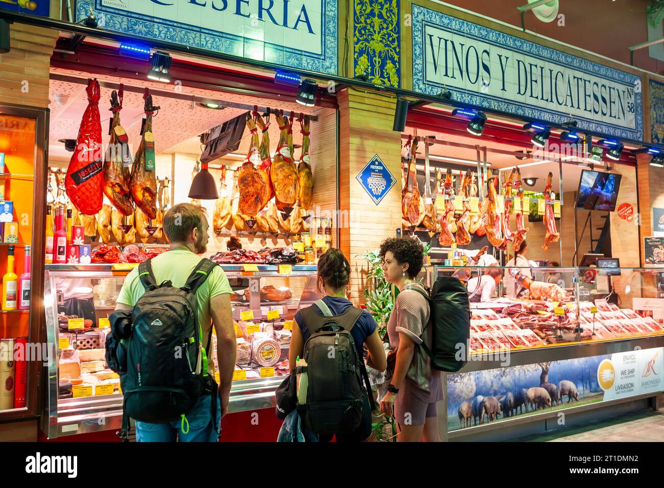 Sevilla, Spanien, Kleingruppen, Touristen mit Rucksäcken, Einkaufen, im überdachten öffentlichen spanischen Lebensmittelmarkt, „Mercado de Triana“ Delicatessen Shop Stockfoto