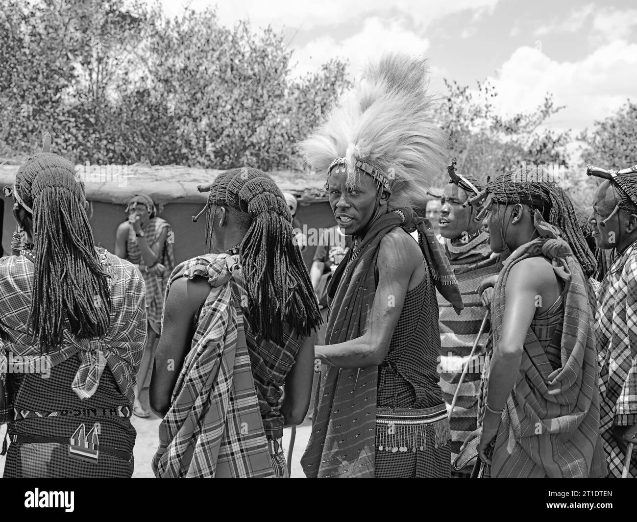 Stammesbewohner von Maasai Mara, Kenia, unterhalten die Besucher aus dem Ausland in ihr Dorf, während man sich dreht und in die Kamera schaut Stockfoto