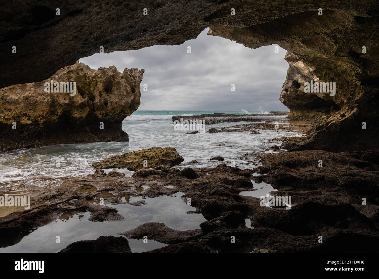 Wenn Sie von der Höhle aus blicken, offenbart sich ein felsiger Felsvorsprung, der vom Meer umgeben ist, während das Innere der Höhle mit einer Reihe von Felsen gefüllt ist Stockfoto